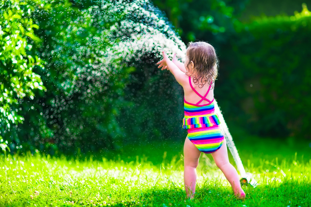 little girl playing with a sprinkler at daycare